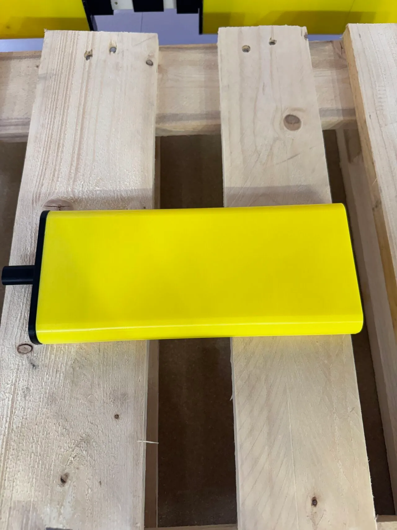 Bumper giallo in TPU appoggiato su un pallet di legno, vista dall’alto